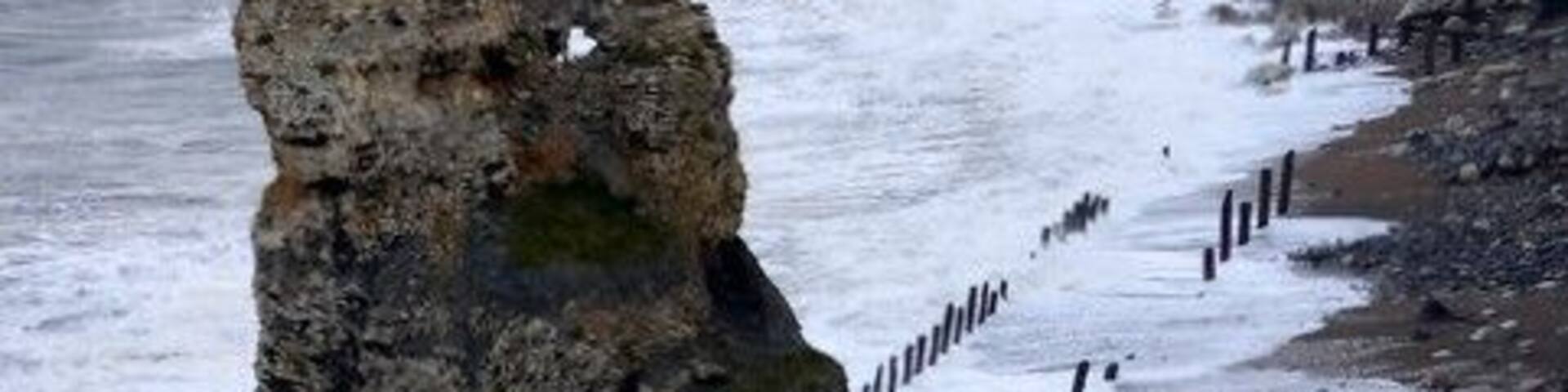 A coastal rock formation with a narrow path beside the sea.