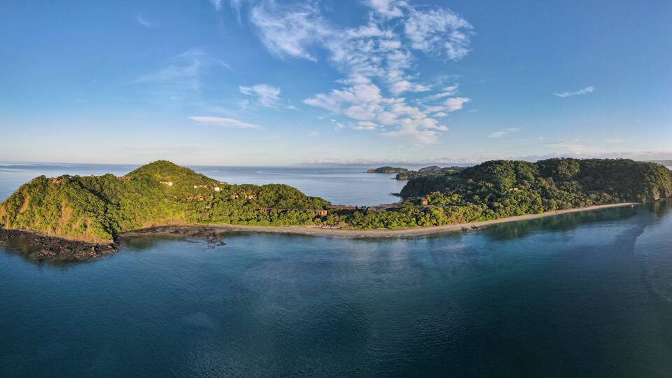 An aerial view of a lush, green island surrounded by calm waters.