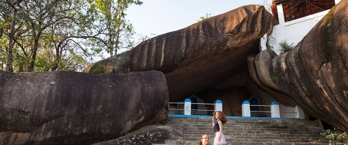 A set of stone steps leading up to a large rock formation with a building in the background.