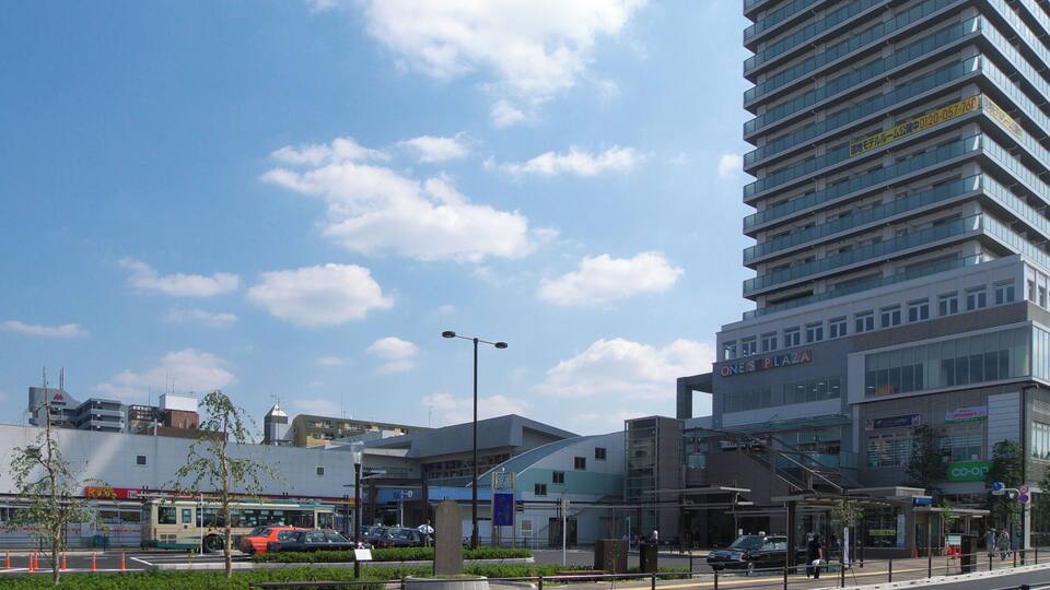 A modern urban street with a tall building, a bus stop, and a pedestrian crossing.