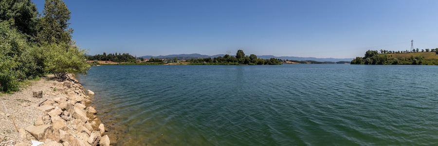 Un río tranquilo con orillas rocosas y montañas a la distancia.