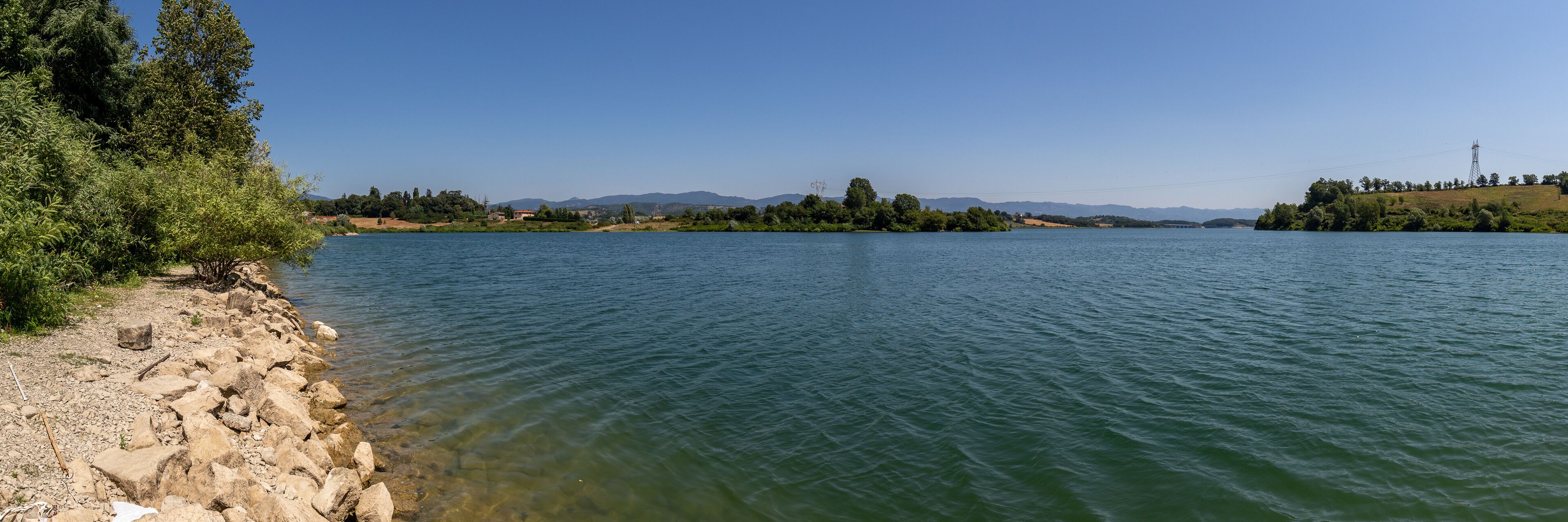 A calm river with rocky shores and distant mountains.