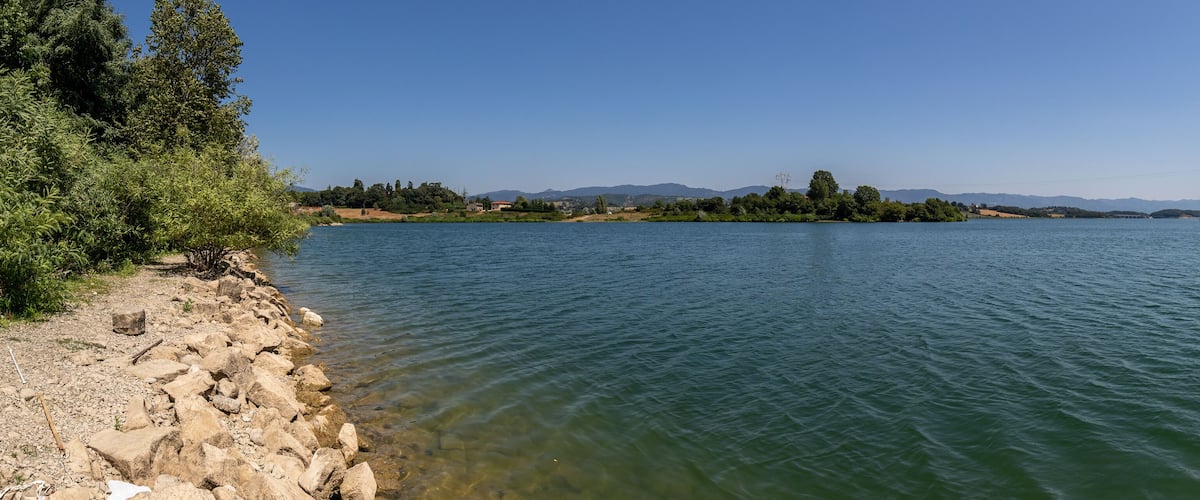 A calm river with rocky shores and distant mountains.