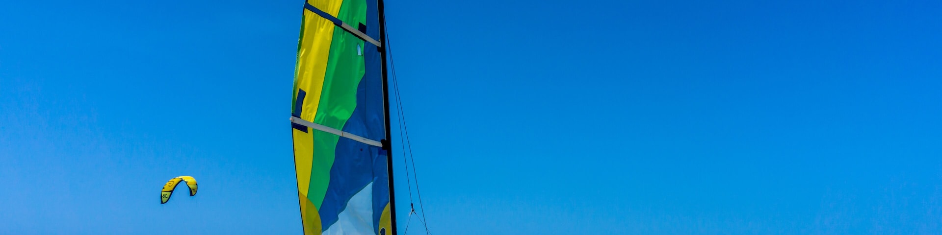 A beach with a sailboat and a parasail.