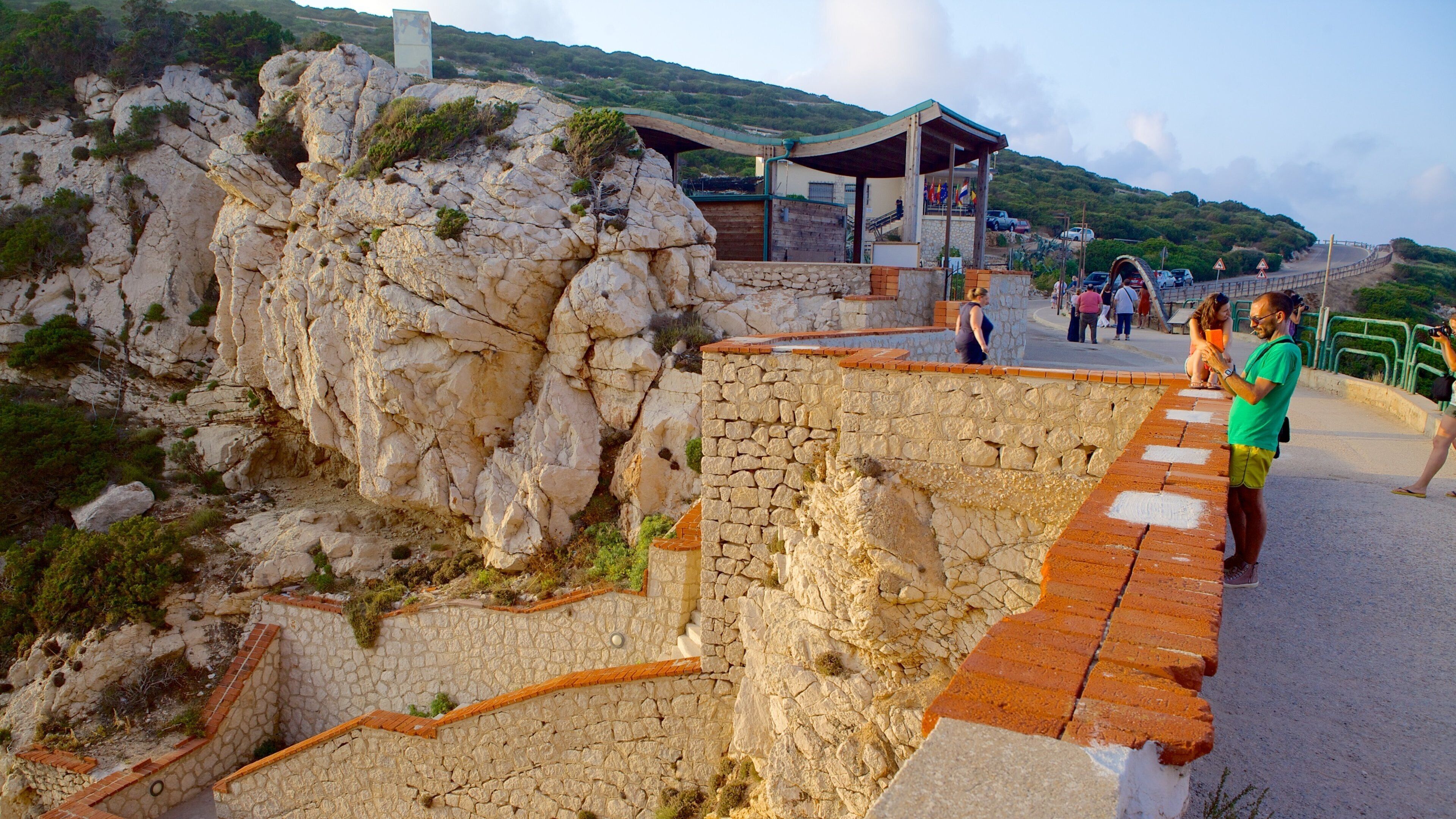 A rocky landscape with a stone wall and a covered walkway.