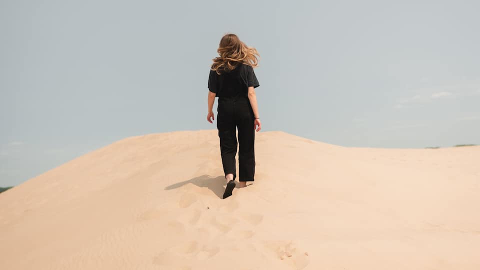 A person walking up a sand dune.