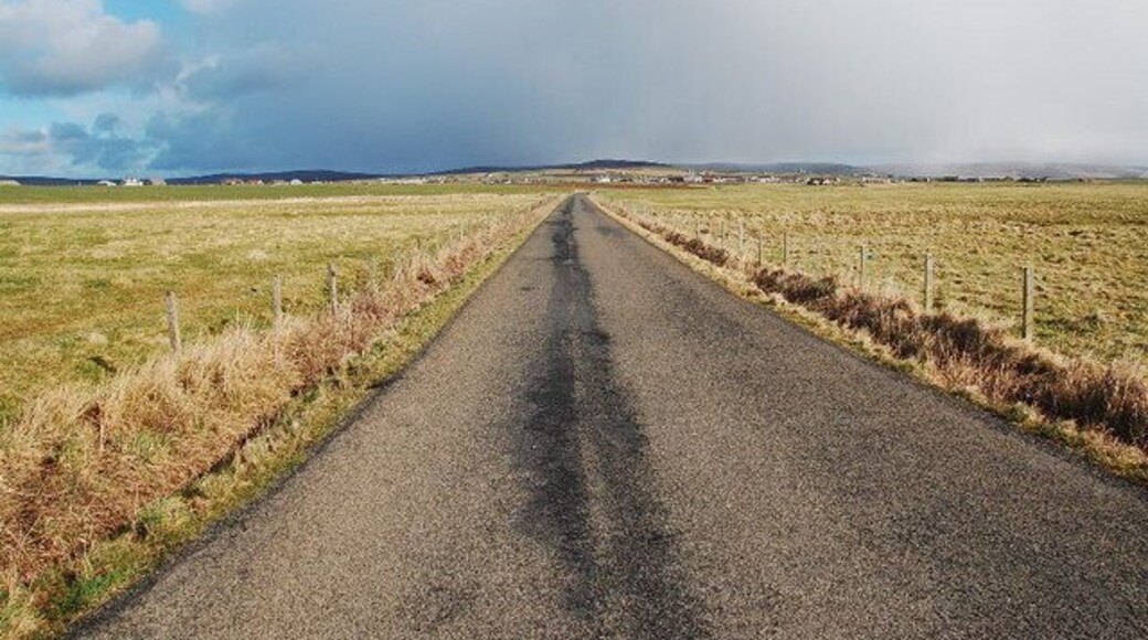 Lane to Dounby Looking eastwards with Dounby on the skyline, about to be swallowed by a stormcloud.
