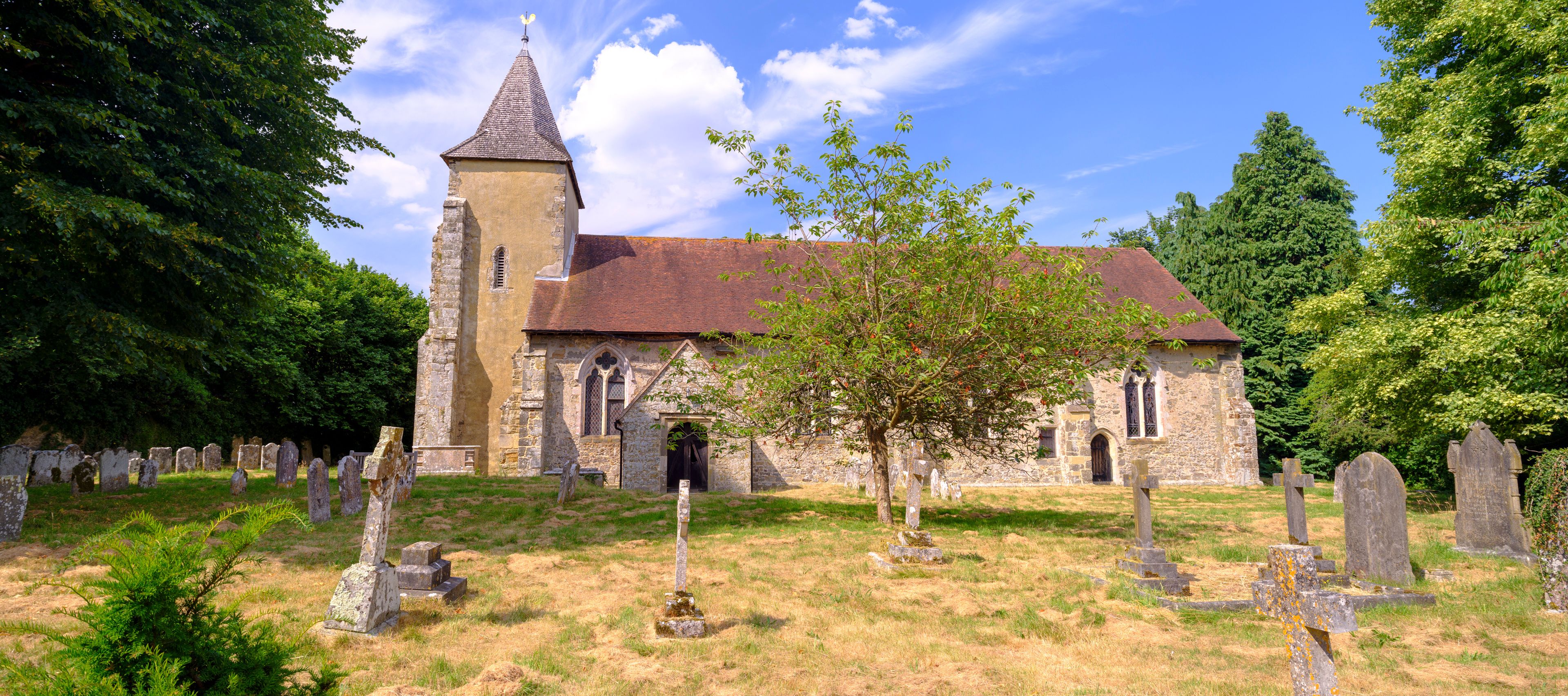 A church with a bell tower, surrounded by a cemetery with gravestones.