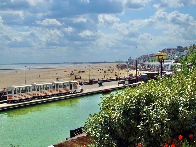 A coastal town with a beach, a promenade, and a waterway with a boat.