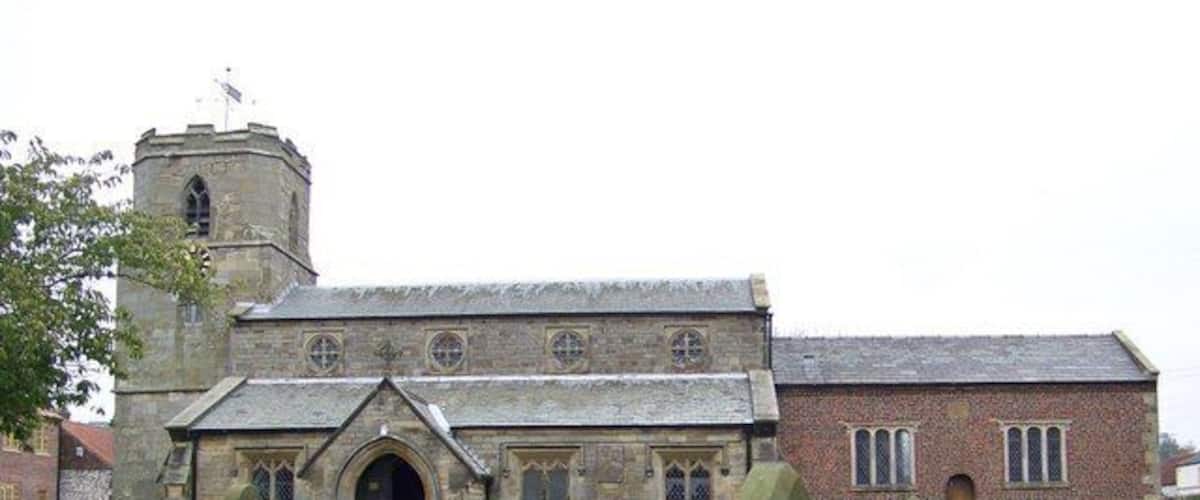 A church with a stone facade, a tower, and a graveyard with headstones.