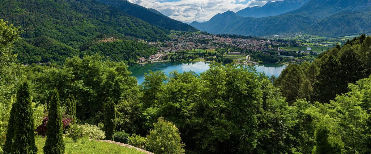A mountainous landscape with a lake, dense greenery, and a small town in the valley.