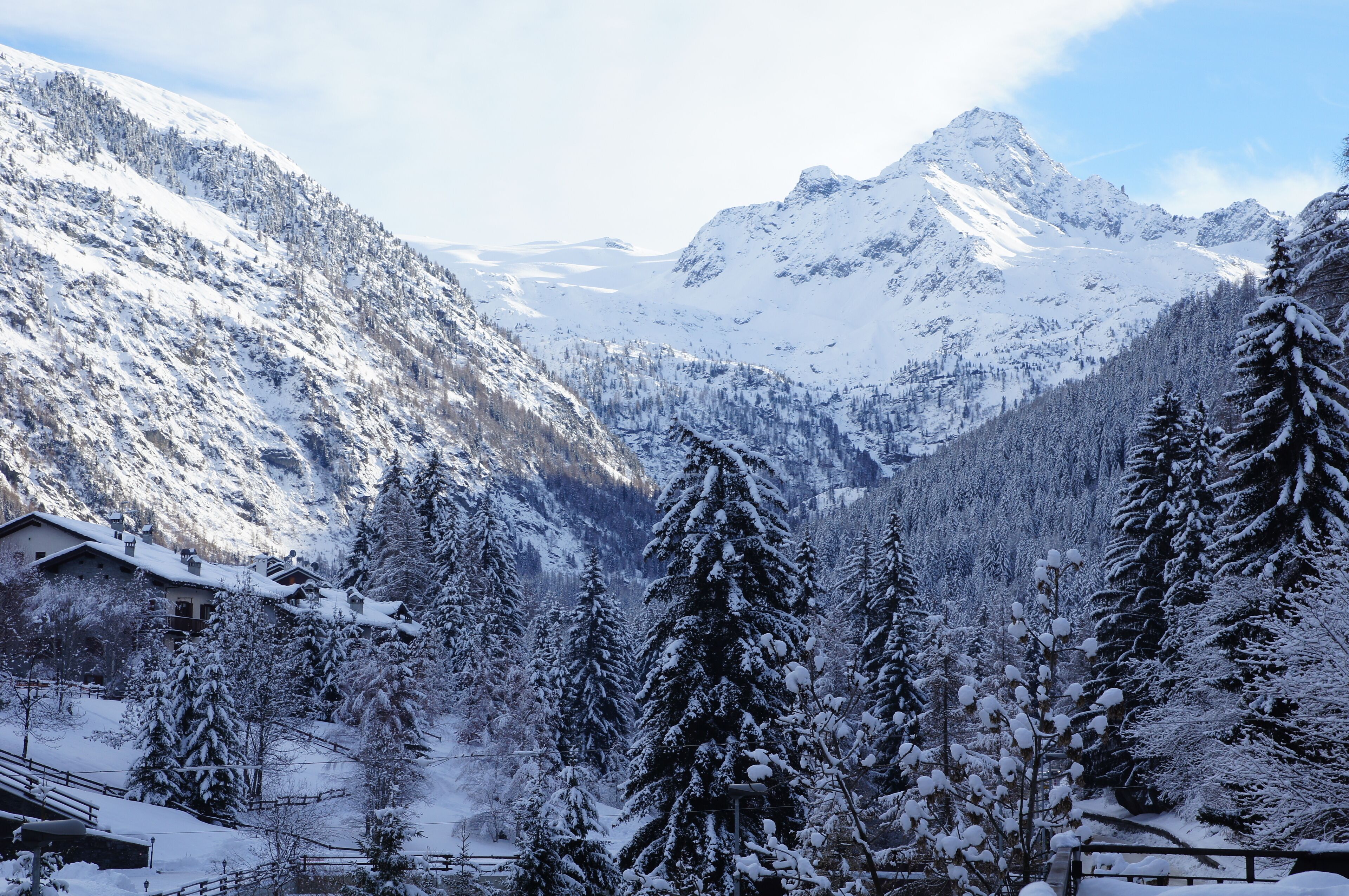 A snow-covered mountain landscape with a cabin and evergreen trees.
