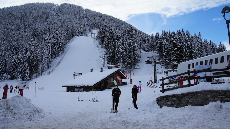 A snowy ski slope with a wooden cabin and a ski lift.