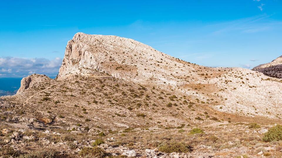 A rugged mountain landscape with rocky terrain and sparse vegetation.