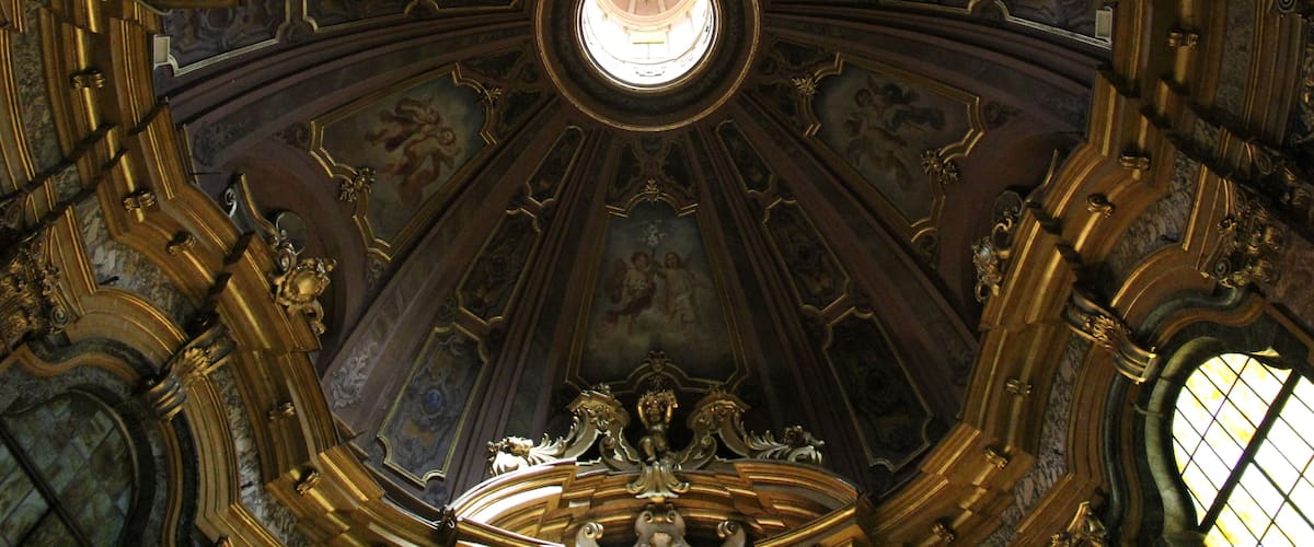 An ornate ceiling with intricate gold detailing and a central circular window.