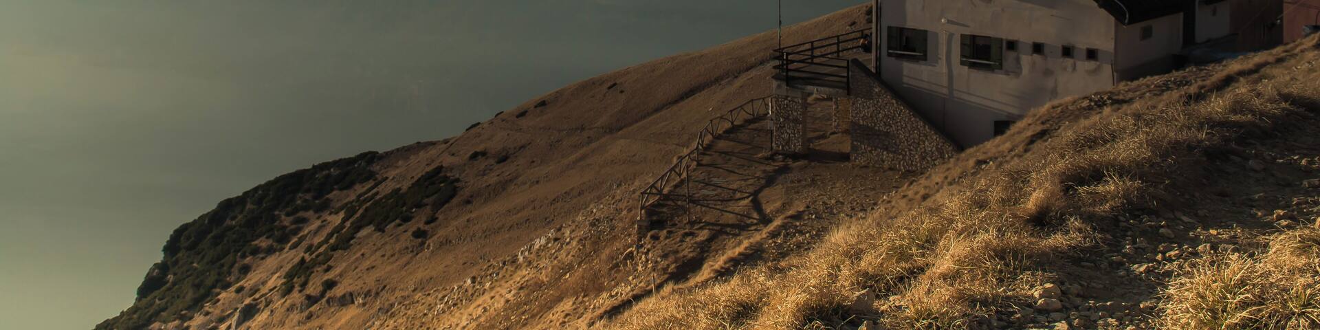 A mountain house with a staircase leading up to it, surrounded by misty mountains.
