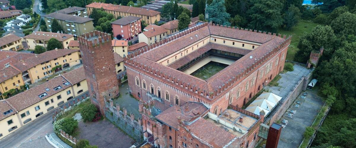 A historic fortress with a central courtyard, surrounded by residential buildings and lush greenery.