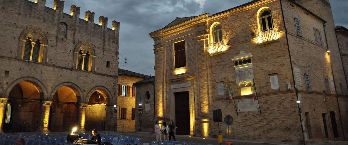 A historic building with arched windows and a tower, illuminated by warm lights.