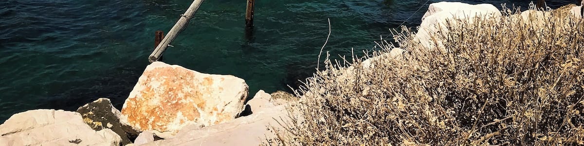 Ein hölzerner Steg erstreckt sich ins Meer, mit einem kleinen Gebäude darauf.