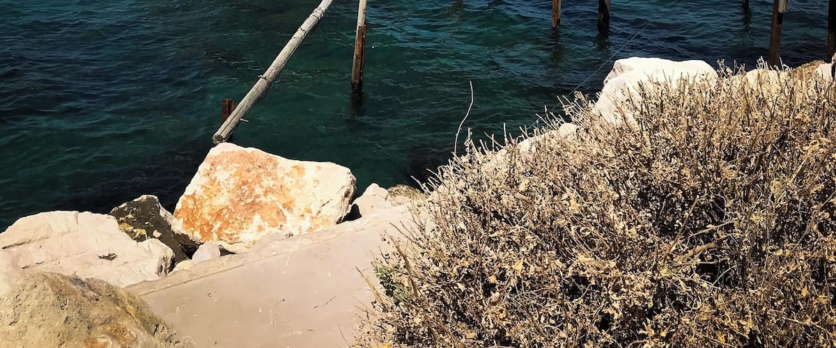 Une jetée en bois s’avançant dans la mer, sur laquelle se trouve un petit bâtiment.