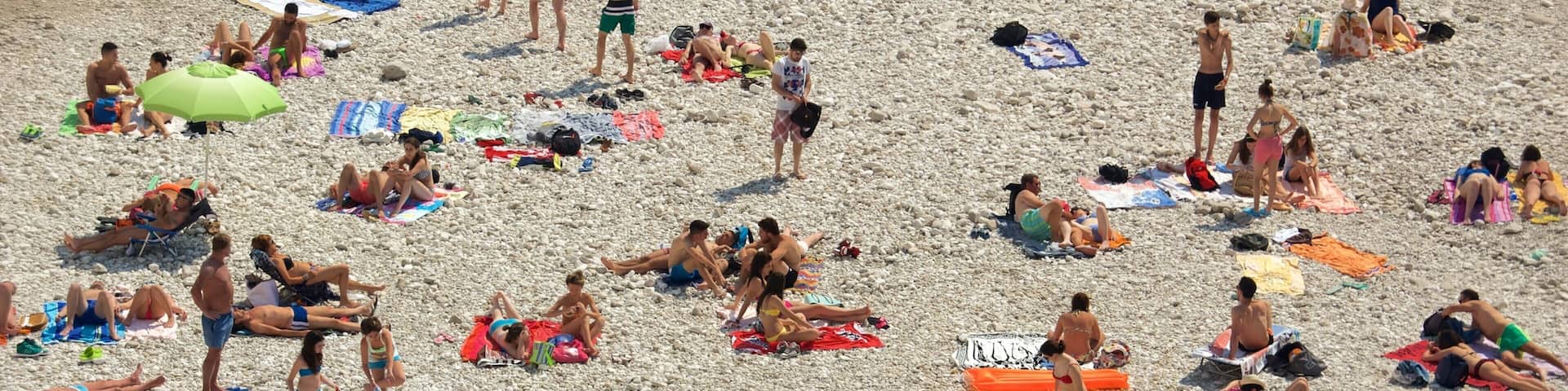 Polignano a Mare showing a pebble beach as well as a large group of people