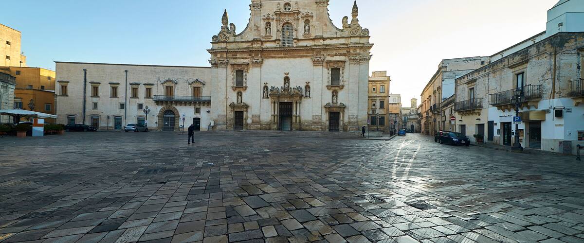 A historic plaza with a prominent church featuring ornate architecture and a cobblestone pavement.