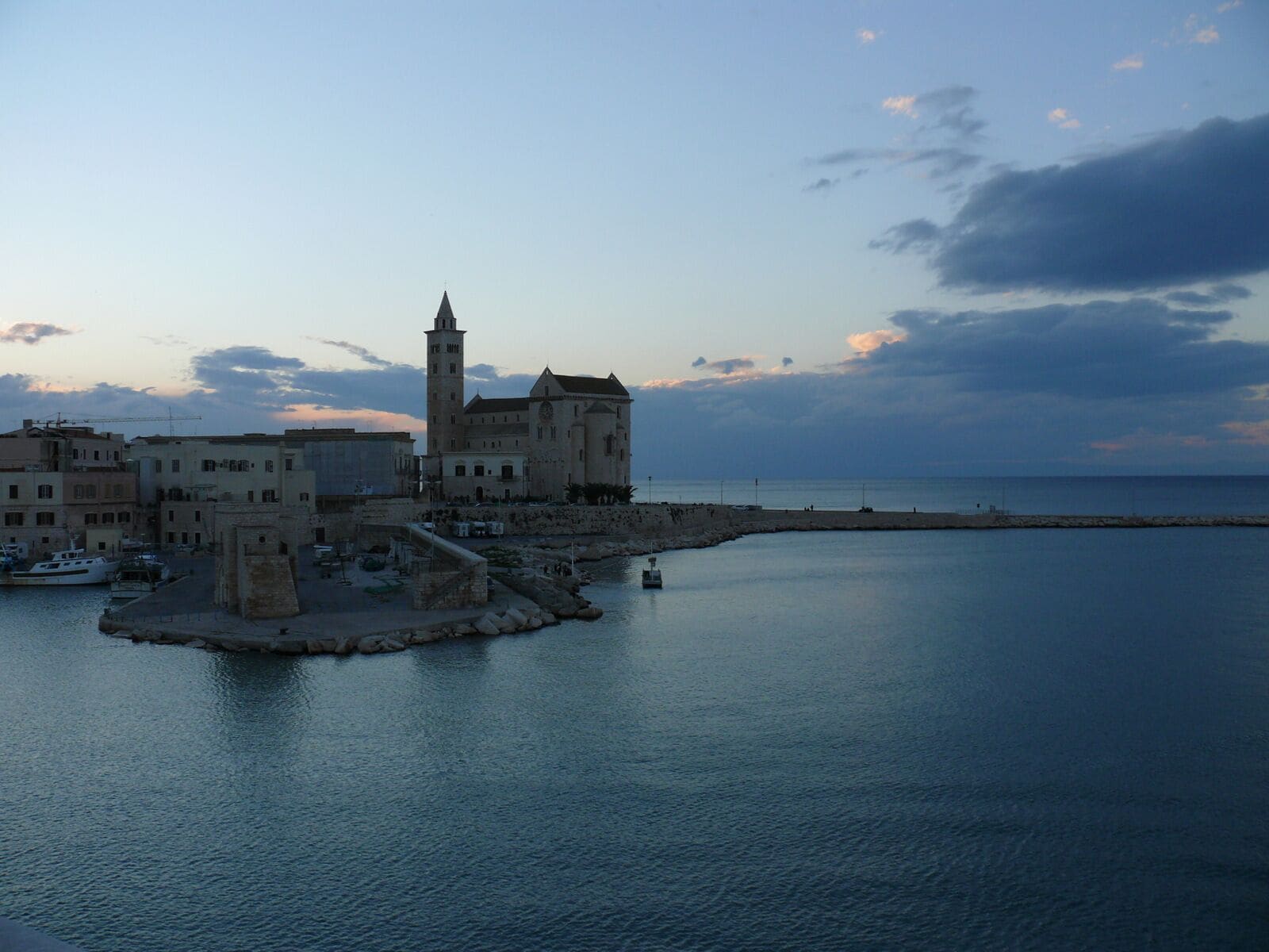 A coastal town with historic buildings, a prominent tower, and a calm sea.
