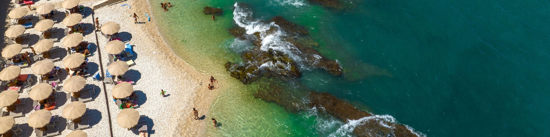 Vista aérea de una playa con muchos sombrillas y gente.