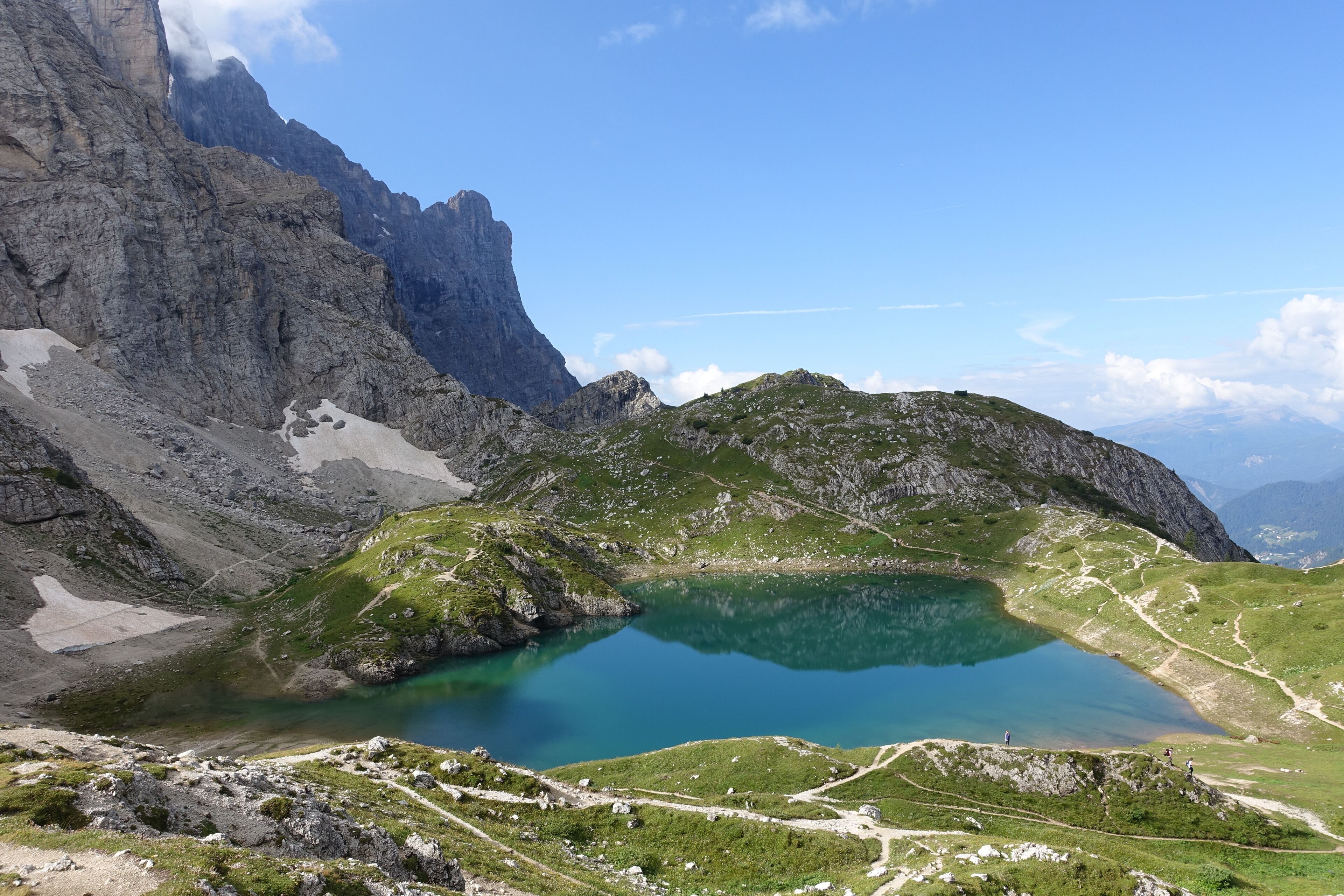 A mountain landscape with a clear lake, rocky terrain, and a distant peak.