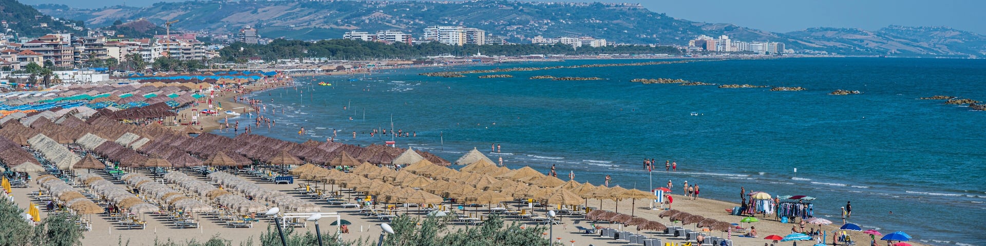 A coastal city with a beach, umbrellas, and buildings.