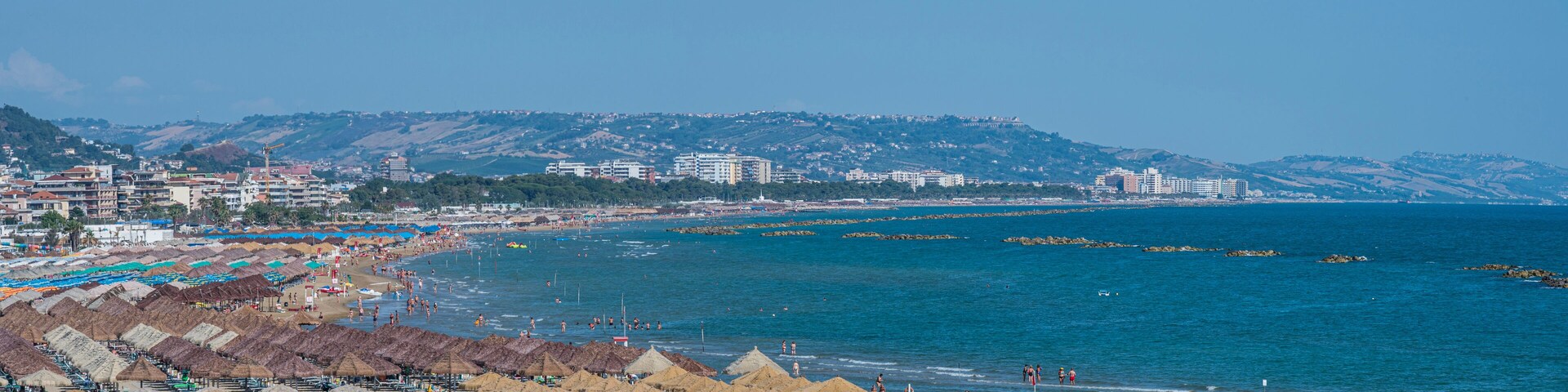 A coastal city with a beach, umbrellas, and buildings.