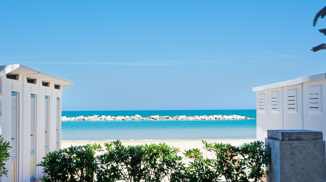 Una spiaggia con acque cristalline blu, edifici bianchi e un litorale roccioso.