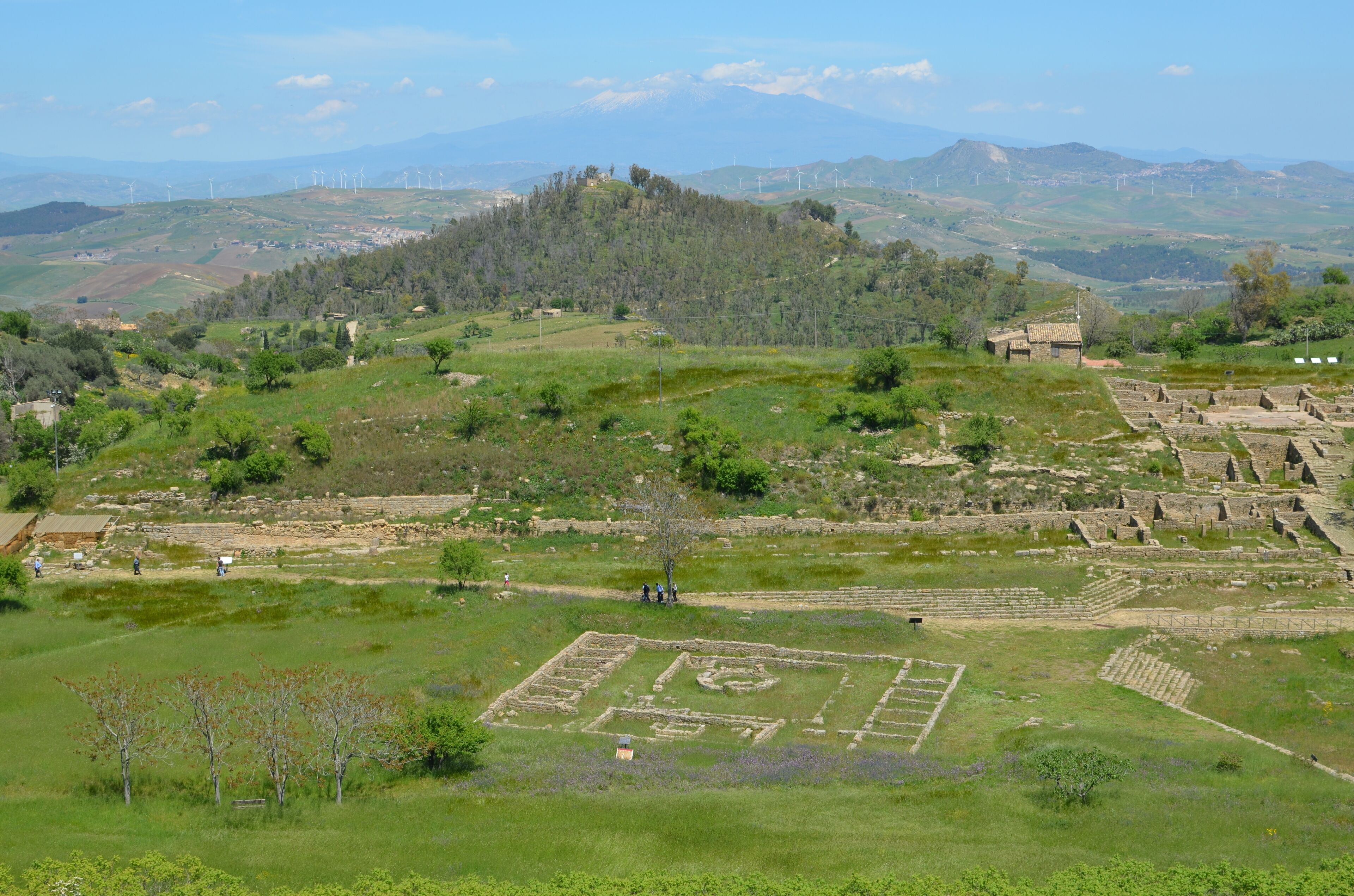 A view of Morgantina's Hellenistic agora. In the foreground the Macellum dating from the Roman period can be seen. In the background the Cittadella hilltop is visible, which was the location of Morgantina's Iron Age settlement. Mount Etna is seen in the far distance.