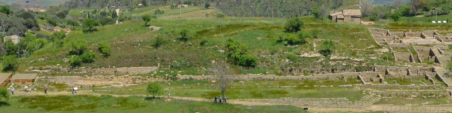 A view of Morgantina's Hellenistic agora. In the foreground the Macellum dating from the Roman period can be seen. In the background the Cittadella hilltop is visible, which was the location of Morgantina's Iron Age settlement. Mount Etna is seen in the far distance.