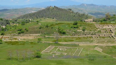 An archaeological site with ancient ruins and wind turbines in the background.