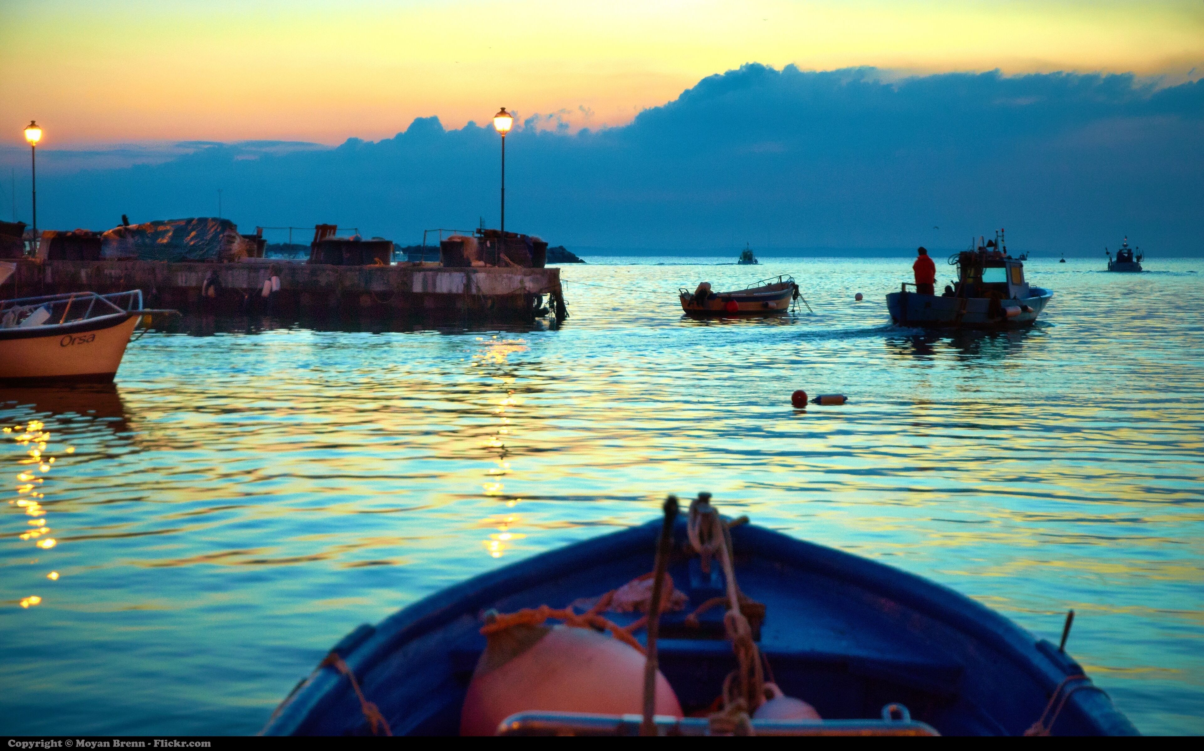 A harbor at sunset with boats and a pier.