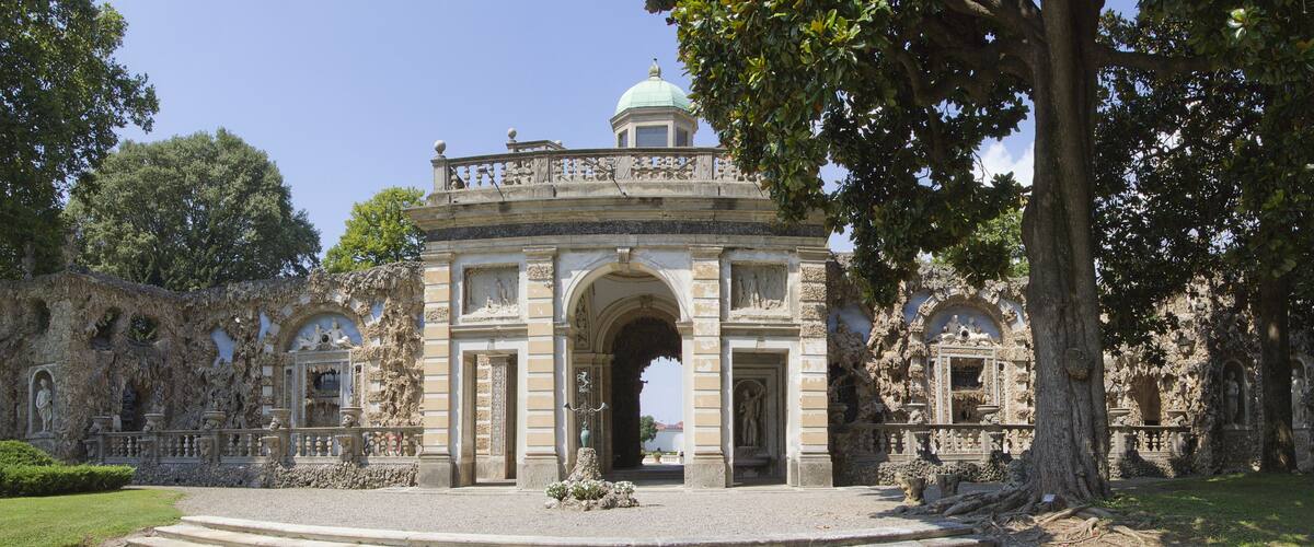 A historic building with a central dome, ornate arches, and statues.