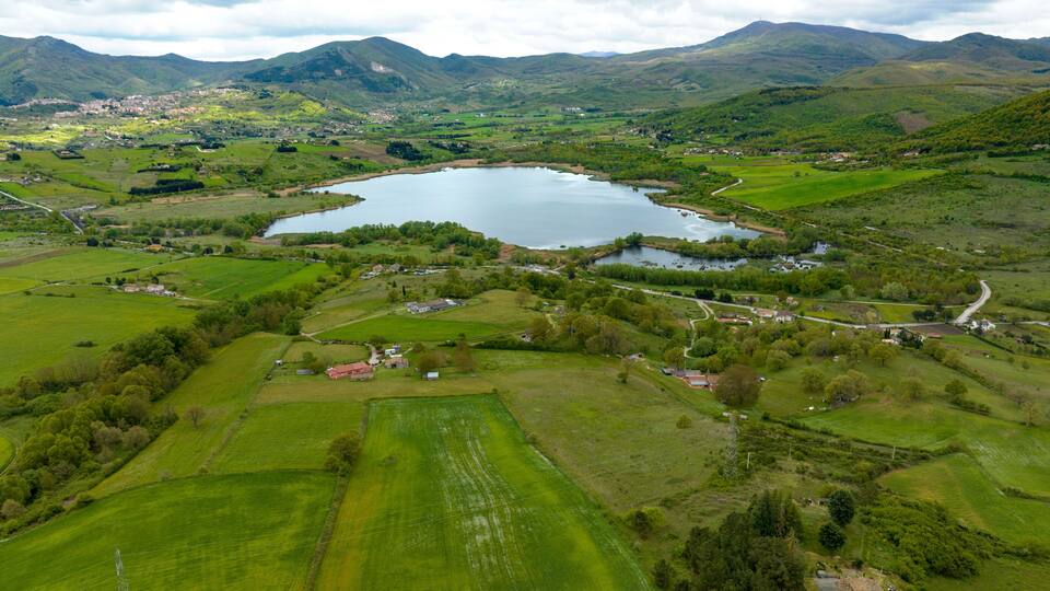 A lake surrounded by green fields and mountains.