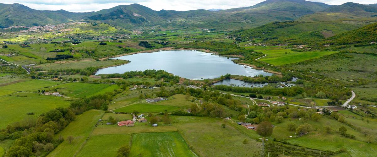 A lake surrounded by green fields and mountains.