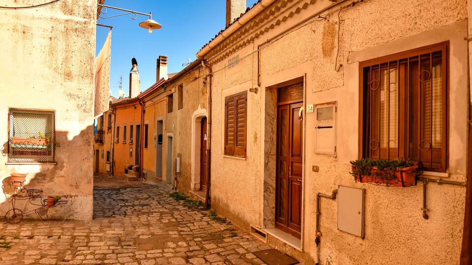 A cobblestone street in a historic town with old buildings, wooden doors, and a bicycle.