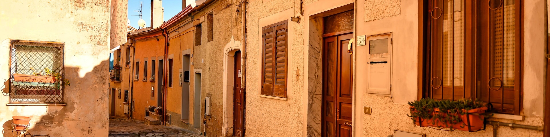 A cobblestone street in a historic town with old buildings, wooden doors, and a bicycle.