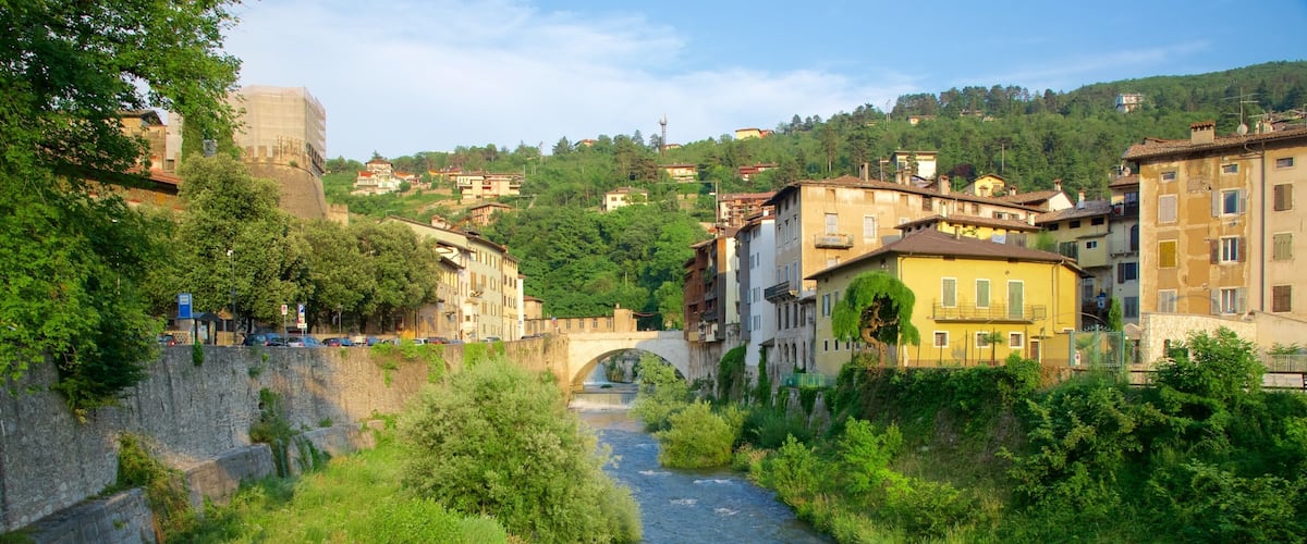 A river flowing through a town with historic buildings and a stone bridge.