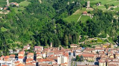 A town nestled in a valley with vineyards and a prominent tower.