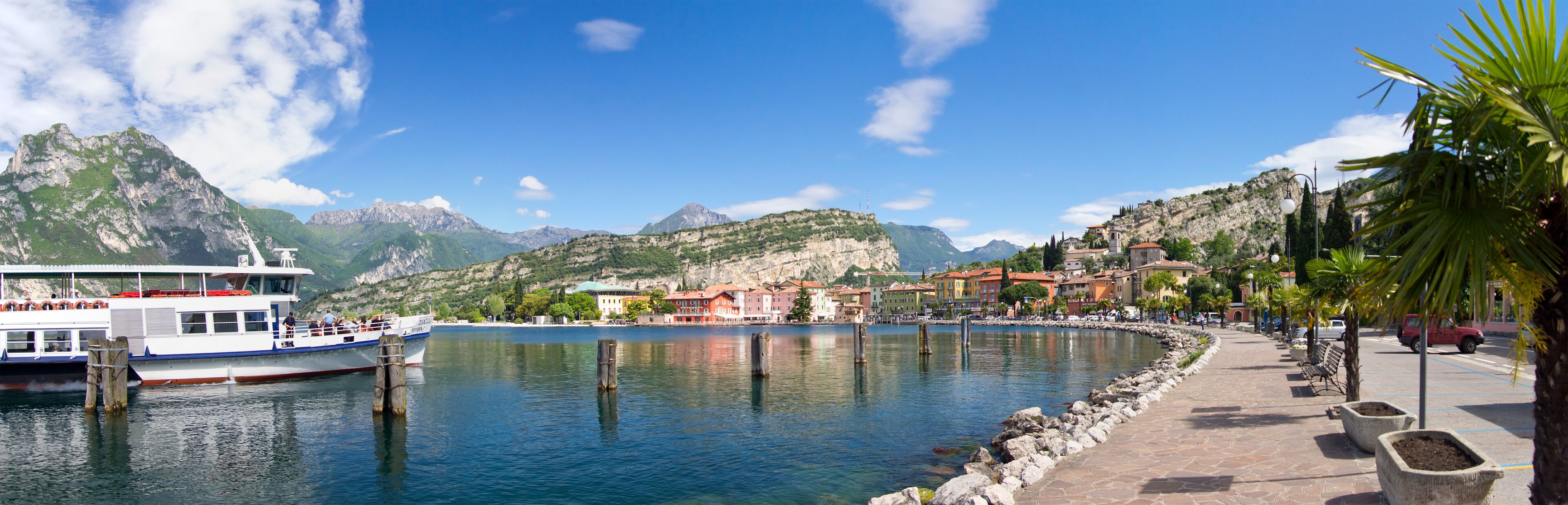 A boat docked at a waterfront with a mountainous backdrop and colorful buildings along the shore.