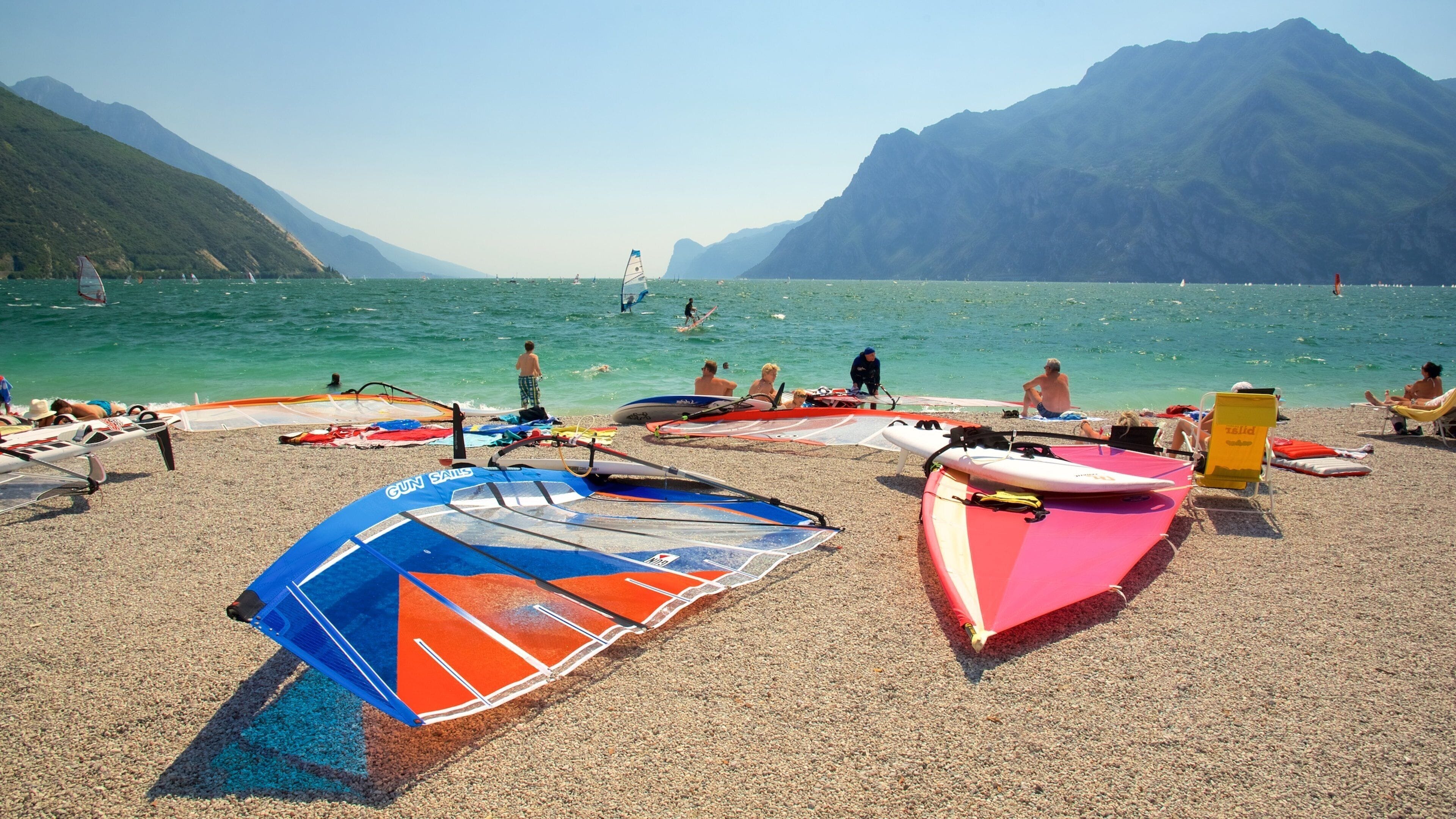 A beach with windsurfing equipment and people relaxing.