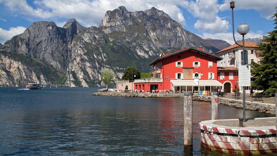 A lake with a red building and mountains in the background.