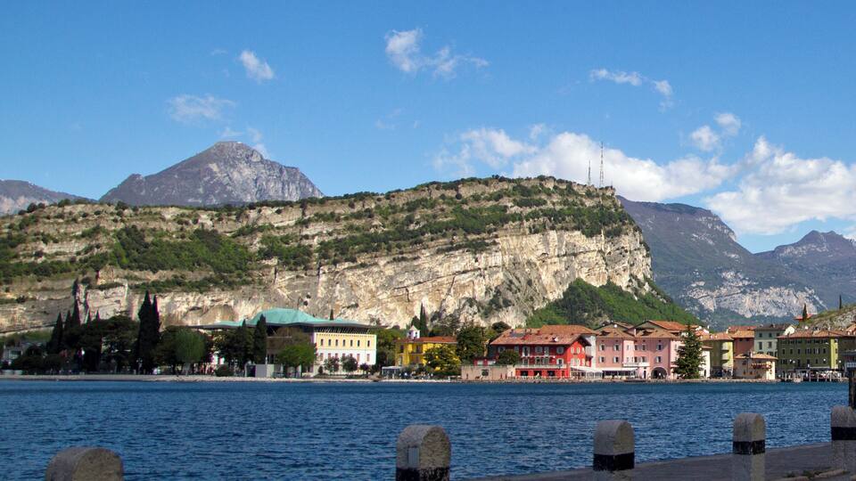 A waterfront with colorful buildings, a mountain in the background, and a clear blue sky.