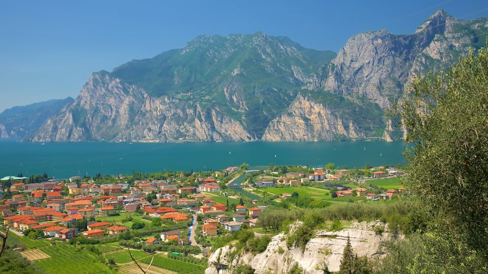 A coastal town with red-roofed houses, a river, and mountains in the background.