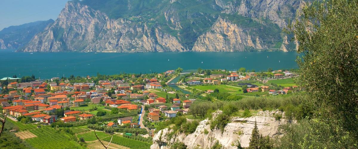 A coastal town with red-roofed houses, a river, and mountains in the background.