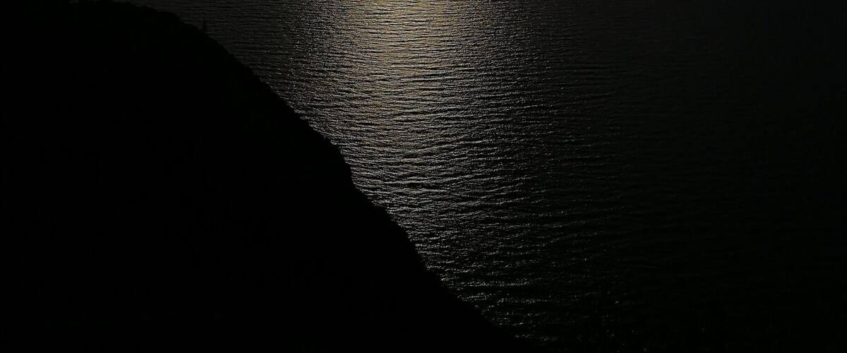 A sunset over a calm sea with mountains in the background.